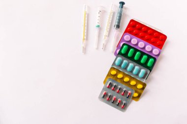 Çeşitli tıbbi ekipmanlar, termometre, ampuller, boru, uyuşturucu, tabletler, kapsüller, sprey, yama, şırınga, beyaz arka planda şişeler. İlaç.,