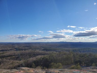Güneş doğarken kayalık bir dağdan ormandaki güzel yeşil ağaçların manzarası.