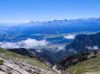 Bulutlu bir gökyüzünün altında güzel bir dağ ve vadi görüntüsü.