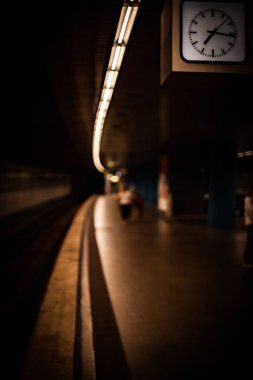 Metro istasyonunda asılı duran bir saatin manzaralı dikey çekimi.