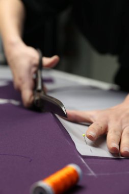 Genç bir kadın tasarımcının elbise yapmak için ölçü alırken çekilmiş dikey bir fotoğrafı.