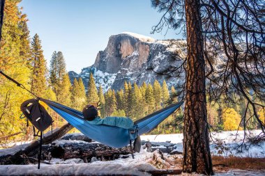 Yarı kubbeli Yosemite Milli Parkı 'nın manzarasının tadını çıkaran bir hamakta bir adam.