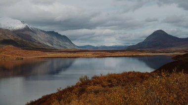 Güzel Denali Gölü bulutlu bir günde Alaska Dağlarını yansıtıyor.