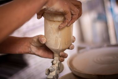 Çömlekçi çarkının aletini çömlek atölyesinde tutan zanaatkârın yakın plan fotoğrafı.
