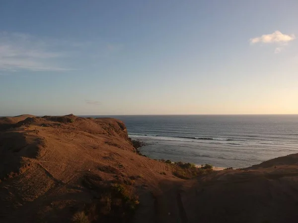背景には穏やかな青い海と夕日と水平線の丘 — ストック写真