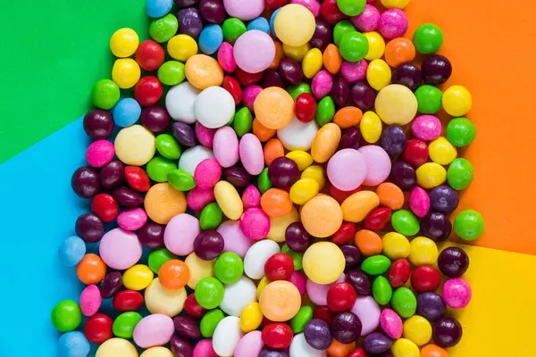 Pionowe Ujęcie Wielu Kolorowych Małych Okrągłych Cukierków Razem Kolorowym Stole — Zdjęcie stockowe