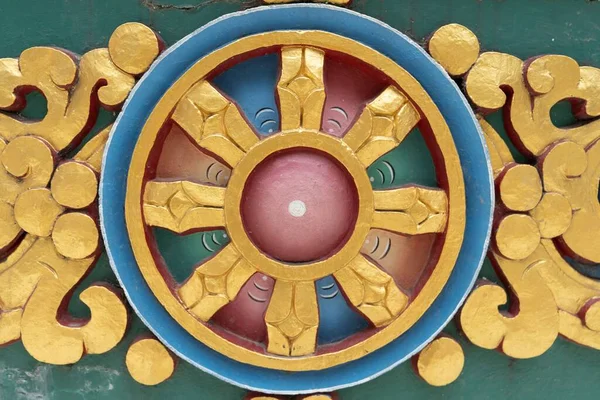 A closeup of a round Buddhist Dharma Wheel in golden blue and red colors