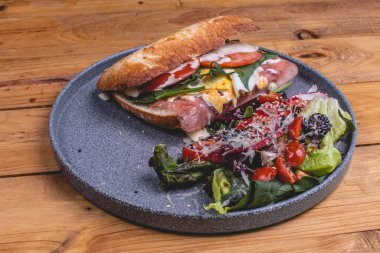 Lezzetli bir jambonlu sandviçin ve restoranda taze bir salatanın yakın çekimi.