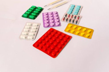 Çeşitli tıbbi ekipmanlar, termometre, ampuller, boru, uyuşturucu, tabletler, kapsüller, sprey, yama, şırınga, beyaz arka planda şişeler. İlaç.,
