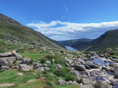 Glendalough Ulusal Parkı 'ndaki taşların, dağların ve nehrin yakın çekim görüntüsü.