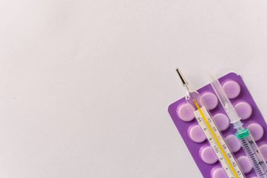 Çeşitli tıbbi ekipmanlar, termometre, ampuller, boru, uyuşturucu, tabletler, kapsüller, sprey, yama, şırınga, beyaz arka planda şişeler. İlaç.,