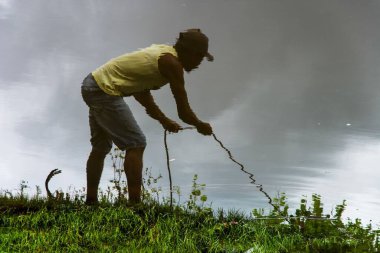 Bahia 'nın Aratuipe şehrindeki Jaguaripe Nehri' nin kıyısında ip çeken bir adamın sudaki yansıması..