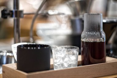 Bir fincan dolusu buz ve bir bardak dolusu kahveyi ahşap tepside yakın plan çekeceğiz.