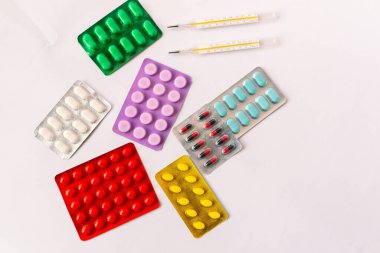 Çeşitli tıbbi ekipmanlar, termometre, ampuller, boru, uyuşturucu, tabletler, kapsüller, sprey, yama, şırınga, beyaz arka planda şişeler. İlaç.,