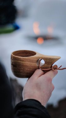 Bulanık kar tarlasına karşı ahşap bir bardak tutan bir adam.