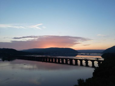 Güneş suyun üzerinde batıyor ve bir köprü uzakta.