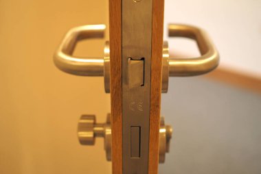 Yarı açık ahşap bir kapının metalik sapının yakın çekimi.