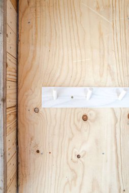 Parlak ahşap duvardaki beyaz askının dikey görüntüsü.