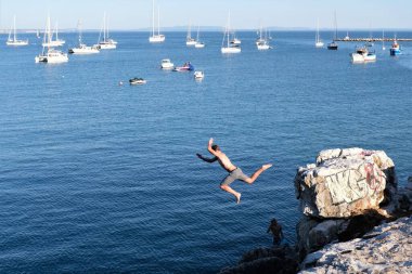 Portekiz 'in Lizbon eyaletindeki Cascais bölgesinde deniz suyuna dalan genç bir adam.