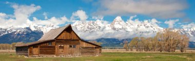 Arkasında karlı dağlar olan tarihi T.A. Moulton Barn 'ın panoramik görüntüsü.