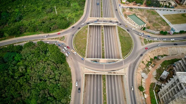 加纳绿树环绕着经过的汽车的圆形道路的航拍 — 图库照片