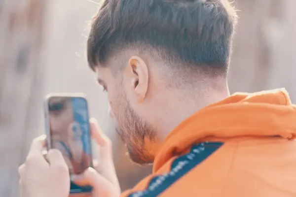 Een Blanke Man Een Oranje Jasje Die Naar Zijn Smartphone — Stockfoto