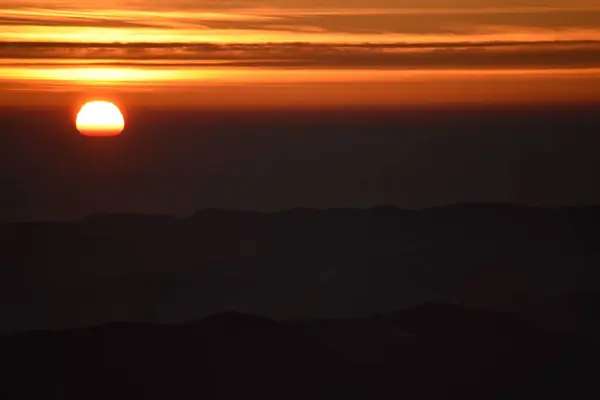 丘のシルエットの上に魅惑的な夕日 — ストック写真