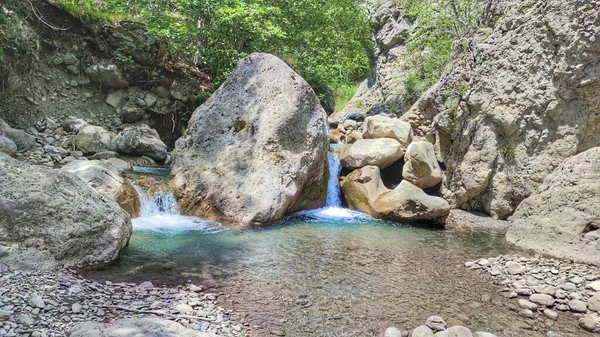 岩に囲まれた池の中に滝が流れる大自然の中の美しい風景 — ストック写真