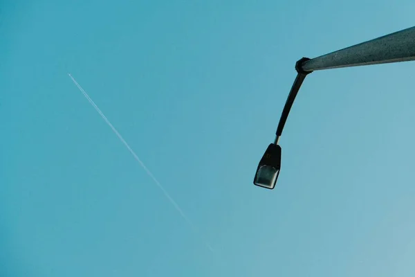 街灯和在蓝天中飞行的飞机的低角度镜头 — 图库照片