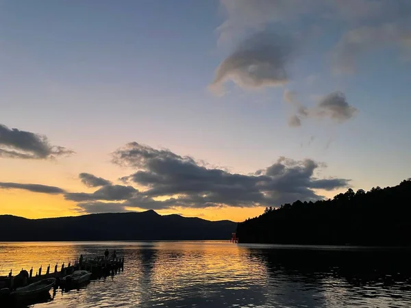 Piękny Widok Jezioro Otoczone Sylwetkami Wzgórz Drzew Pod Zachmurzonym Niebem — Zdjęcie stockowe