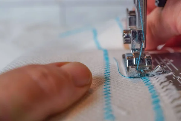 白い布に青い糸を縫いつけたミシン針のクローズアップ — ストック写真