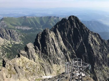 Güneşli bir günde, kayalık dağların tepesindeki elektrik direğinin kuş bakışı görüntüsü.