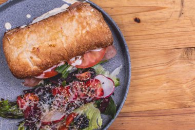 Lezzetli bir jambonlu sandviçin ve restoranda taze bir salatanın üst görüntüsü.