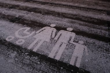 Kısmen karla kaplı bir caddenin ve bir aile park yeri tabelasının yakın çekimi.