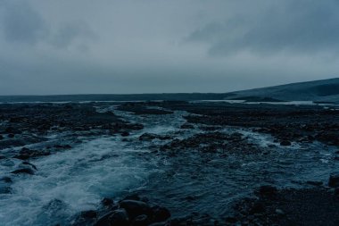 Bulutlu gökyüzünün arka planında kayalık kıyı.