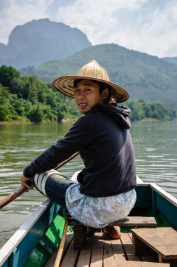 Nong Khiaw Dağları 'ndaki Nam Ou Nehri' ndeki teknede hasır şapkalı Asyalı çocuk, Laos, dikey.