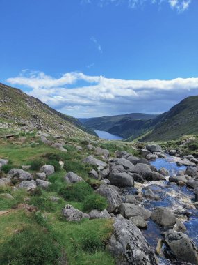 Glendalough Ulusal Parkı 'nda taşların, dağların ve nehrin dikey görüntüsü.