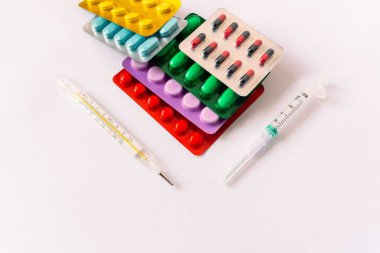 Çeşitli tıbbi ekipmanlar, termometre, ampuller, boru, uyuşturucu, tabletler, kapsüller, sprey, yama, şırınga, beyaz arka planda şişeler. İlaç.,