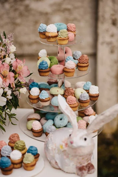 テーブルの上にカラフルなカップケーキと装飾的なウサギ イースターフェスティバルのコンセプト — ストック写真