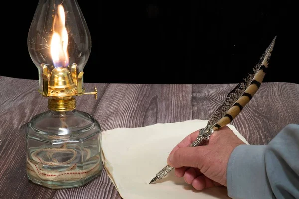紙に掛け軸ペンで書く人とオイルランプのクローズアップショット — ストック写真