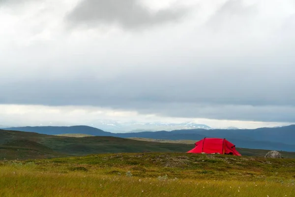 Een Rode Tent Een Grazig Weiland Onder Een Bewolkte Lucht — Stockfoto