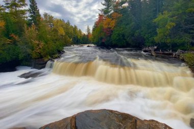 Michigan 'daki Tahquamenon Şelalesi' nin uzun bir görüntüsü sonbahar yapraklarıyla çevrili.