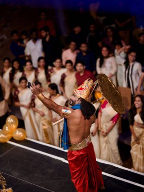 Onapottan rolündeki bir adam Onam festivali sırasında sahnede şemsiyeyle