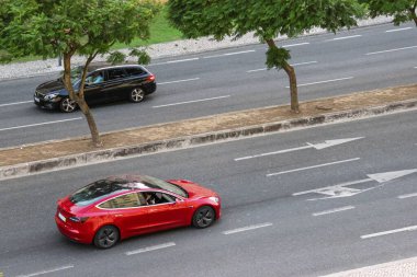 Kırmızı bir 2021 Tesla Model 3 ve Peugeot 308 Lizbon sokaklarında