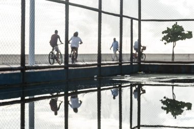 Öğleden sonra Rio Vermelho sahilinden geçen bisikletçiler Salvador, Bahia 'da.