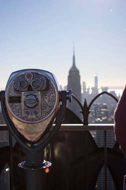 Manhattan şehrinin arka planına sahip madeni parayla çalışan bir dürbünün dikey çekimi.