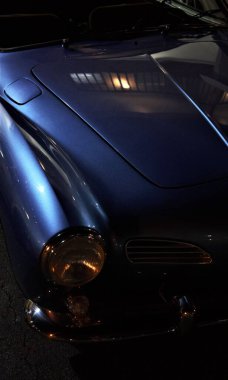 Klasik mavi bir arabanın ön detaylarının dikey çekimi.