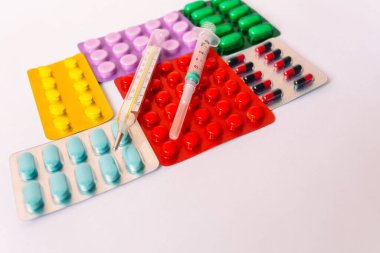 Çeşitli tıbbi ekipmanlar, termometre, ampuller, boru, uyuşturucu, tabletler, kapsüller, sprey, yama, şırınga, beyaz arka planda şişeler. İlaç.,