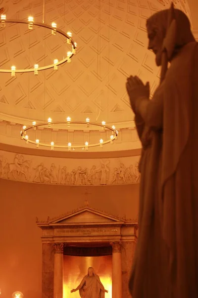 Pionowe Ujęcie Wnętrza Kościoła Posągami Oświetlonymi Żyrandolami — Zdjęcie stockowe