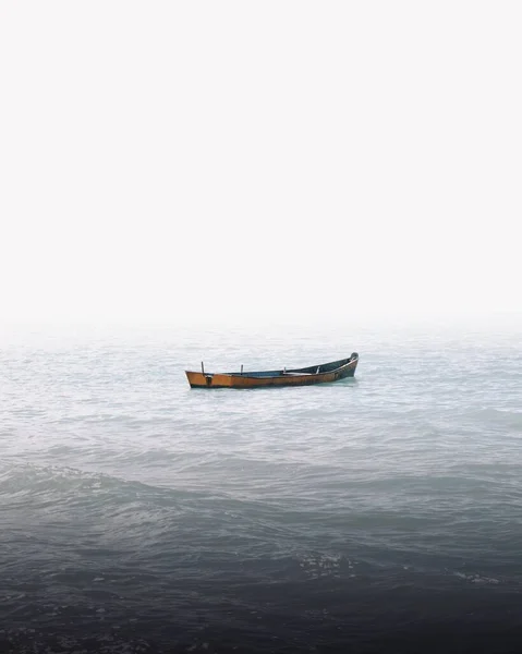 Вертикальный Снимок Одинокой Лодки Морских Волнах Покрытых Туманом Отлично Подходит — стоковое фото